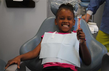 Child smiling holding toothbrush